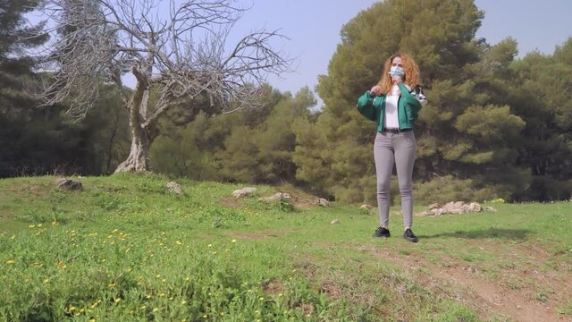 mujer Gemela se quita la mascarilla y estalla de alegr&iacute;a en  un prado con flores amarillas en un bosque