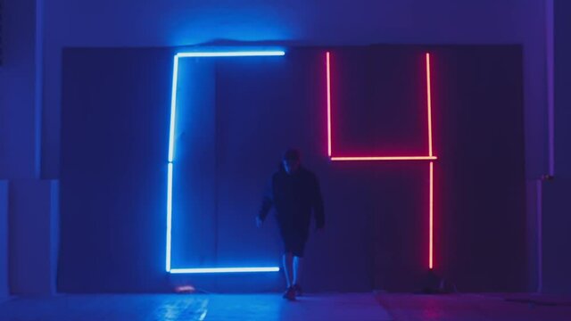 Person in windbreaker and red cap dancing to breakdance on C-4 neon symbol. red and blue  neon background . Flickering neon background . man dancing to breakdance in night club