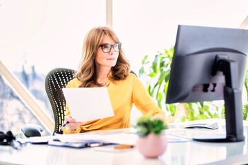 Shot of confident mature woman sitting behind her computer and working