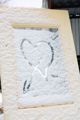 A heart shape painted in the snow on a discarded door.
