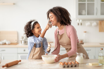 Black woman and daughter cooking and playing with flour
