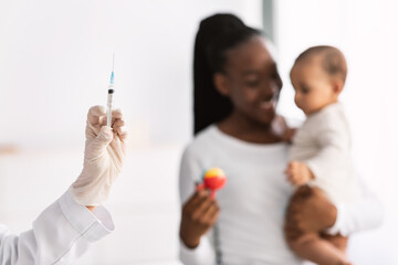 African American mother holding baby for vaccination