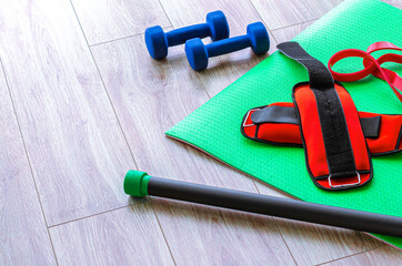 top view of fitness mat with dumbbells and resistance band on background, panoramic shot