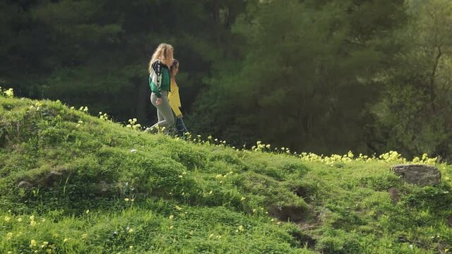 Dos hermanas gemelas pasean por una monta&ntilde;a verde de flores amarillas en un bosque lleno de &aacute;rboles