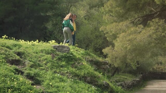 Dos hermanas gemelas pasean por una monta&ntilde;a verde de flores amarillas en un bosque lleno de &aacute;rboles