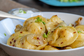 Pelmeni dumplings making process: Cooked pelmeni stuffed with meat in a bowl with seasoning, onions and sour cream. Gluten free recipe for traditional Russian cuisine. handmade ravioli or dumplings.