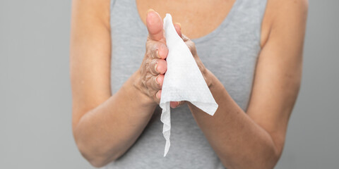 Senior woman cleaning hands with wet wipes - prevention of infectious diseases