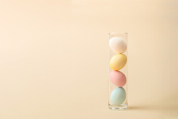 Fototapeta na wymiar Pastel easter eggs in vase on beige background. Minimal zig zag arrangement with copy space.