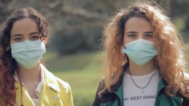 c&aacute;mara girando sobre dos hermanas gemelas pelirrojas con mascarilla , en el bosque