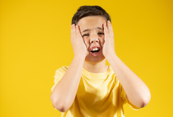 Boy with yellow t-shirt making gesture over yellow background