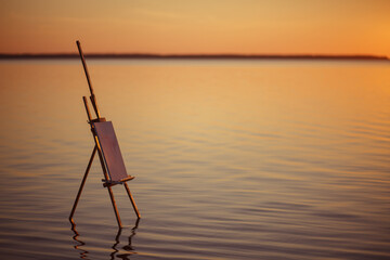 Large salt lake. A wooden easel stands in the water without waves and casts a reflection on the surface. Drawing pictures on the nature. Outdoor hobbies by the sea