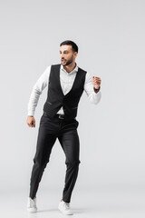 full length view of arabian man in black trousers and vest running on grey