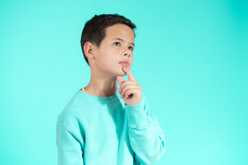 Young beautiful boy pensive isolated over green background