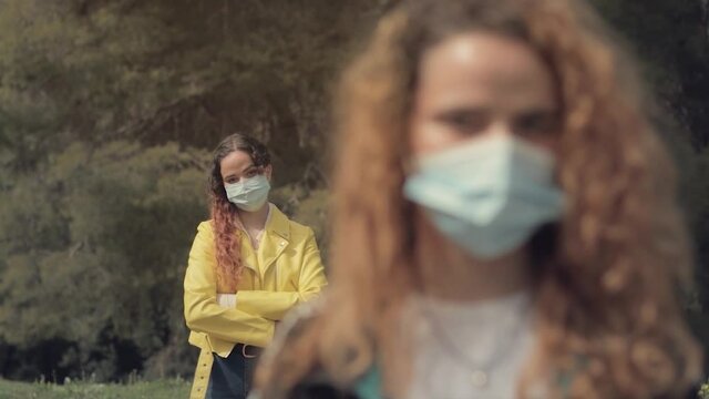 Dos hermanas gemelas pelirrojas, una detr&aacute;s de la otra, en un bosque con &aacute;rboles en el fondo