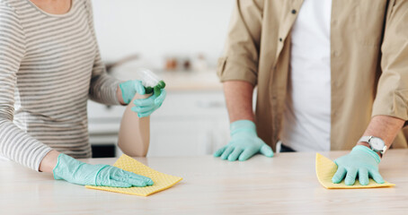 Adult couple in casual clothes, wiping with sponge in modern kitchen