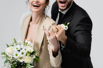 partial view of excited newlywed couple showing wedding rings isolated on grey