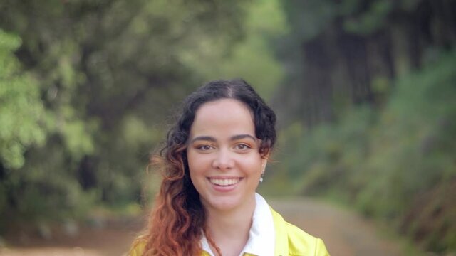 mujer joven pelirroja sonriendo en un camino en el bosque verde cubierto por &aacute;rboles en Espa&ntilde;a