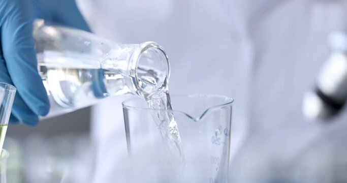 Scientist chemist pouring water from flask into glass 4k movie