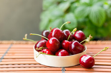 Bowl full of sweet red cherries on brown wooden background. Rustic style. Food banner, Copy space.