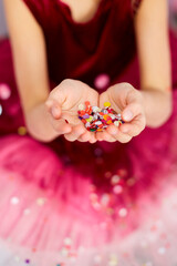 Beautiful little girl blows up multicolored confetti, having fun at home birthday party