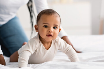 Cute little African American baby crawling in bed