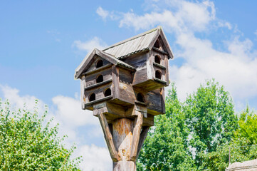 Wooden rural bird feeder with multiple entrances. 