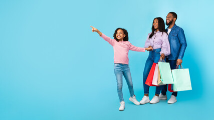 Fototapeta premium African American cheerful people holding shopping bags pointing aside