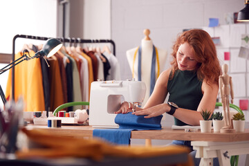Female Student Or Business Owner Working In Fashion Using Sewing Machine In Studio