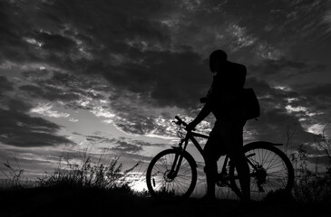 Obraz premium cyclist with a bicycle, in the black background.