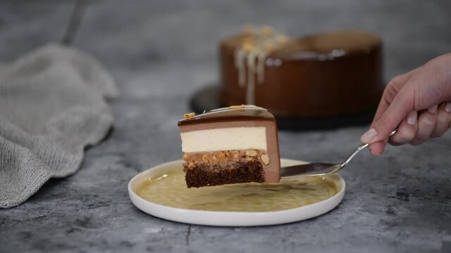 Piece of chocolate caramel peanut mousse cake, snickers on a plate.