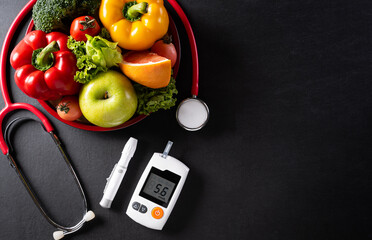 Top view of healthy food in plate with stethoscope and diabetes control on dark background. World health day and medical concept.