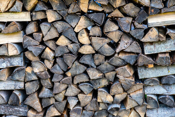 Chipped firewood is on the heap. Woodpile of firewood close-up. A stack of dry firewood, visible texture and cracks in the tree. Exterior shot of a large pile of firewood