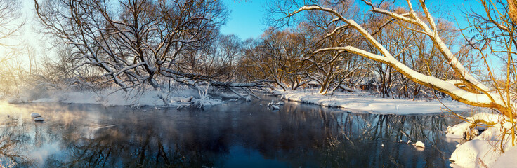 Fototapeta na wymiar Frosty winter panoramic landscape with forest river during sunny january morning.