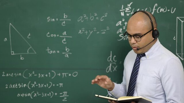 Young asian teacher man teaching video conference with student. Male Indian teacher training the mathematics in classroom from online course. He wearing small talk headset.
