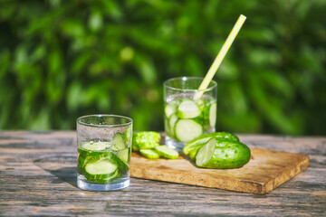 two glasses of fresh cucumber drinking water. sliced cucumbers on cutting board. natural nature. hot summer concept