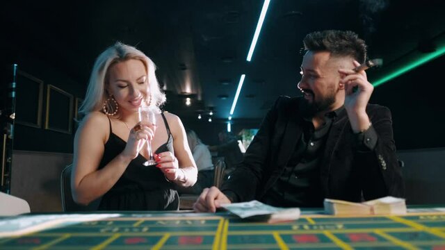 Bearded man with money in a casino. Rich businessman in suit is flirting with a beautiful woman.