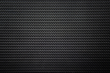 Abstract black background with real metallic surface with round circular holes in it.