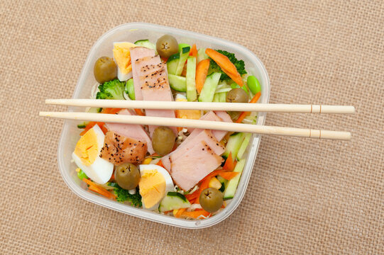 Healthy Chicken Salad With Vegetables In Tupperware With Chopstick. Isolated On Jute Background. Top View