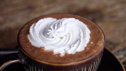 Close up of whipped cream on top of the cocoas in brown mug