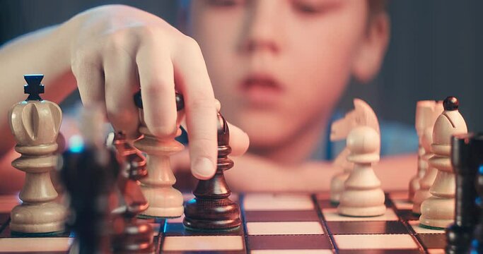 Cute little boy playing chess at home. Smart kids. Game good for brain intelligence concept. Clever concentrated and thinking child while playing chess. Kids early development. Figures on chessboard.
