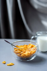 Morning healthy breakfast variety concept. glass bowl of milk next to cornflakes in a glass on a grey background. Top view. Healthy eating.