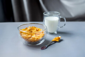 Morning healthy breakfast variety concept. glass bowl of milk next to cornflakes in a glass on a grey background. Top view. Healthy eating.