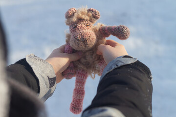 Handmade knitted sheep in the hands of a child in winter