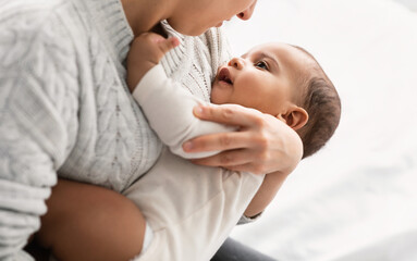Young woman holding cute little African American infant on hands