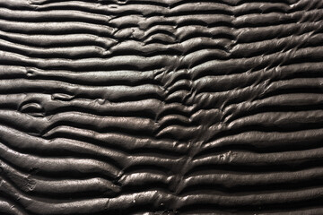 Wavy pattern of sand on a beach.