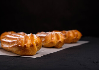 Eclairs with cream on a dark background