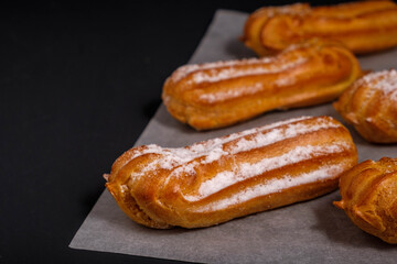 Eclairs with cream on a dark background