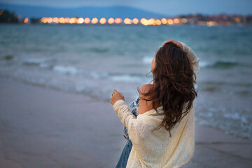 Obraz premium Girl looks at the sea and the city at sunset