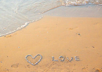 On the sand shells lined with heart and the word love