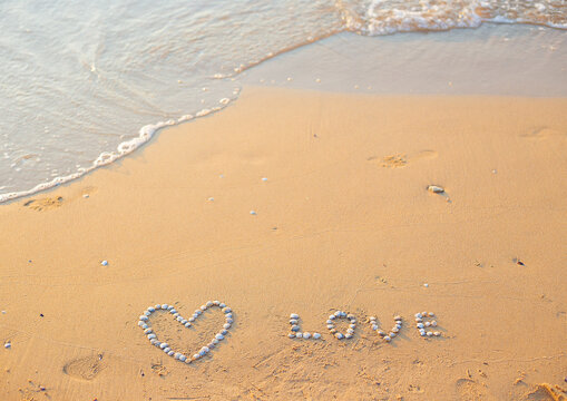 On the sand shells lined with heart and the word love
